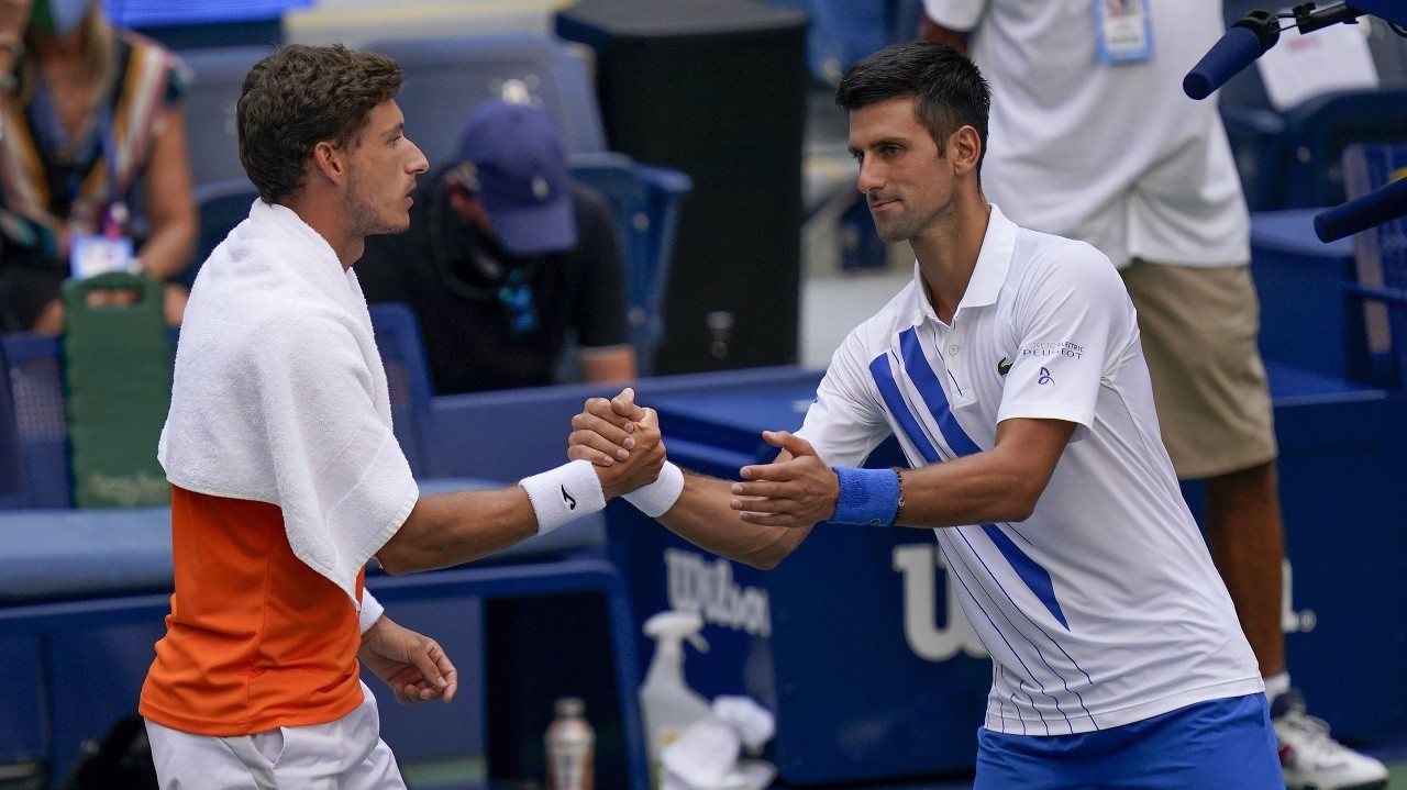 Srbský tenista Novak Djokovič (vpravo) podáva ruku Španielovi Pablovi Carrenovi-Bustovi po tom, čo ho diskvalifikovali.