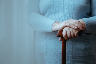 Older lady standing with a wooden walking stick