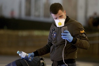 Muž s respirátorom a rukavicami na viedeňskom letisku Schwechat .