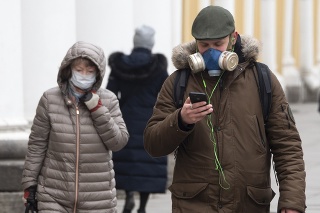 Ľudia s ochranným rúškom a maskou na tvári kráčajú na ulici v Petrohrade.