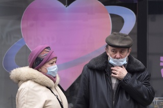 Ľudia s ochrannými rúškami stoja na autobusovej zastávke v Petrohrade.