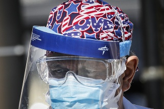 Zdravotník s ochranným krytom na tvári stojí pred zdravotníckym zariadením v New Yorku.