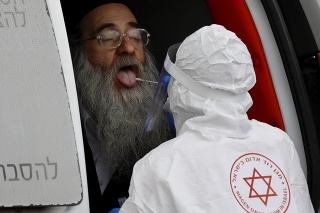 Izraelský zdravotník v ochrannom odeve robí výter z úst ultra-ortodoxnému Židovi.