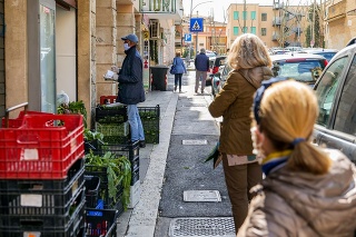 Rome, Italy, March 27 -- Some people protected by a medical mask wait in line and at a safe distance to be able to buy food in a shop in the northern area of Rome.