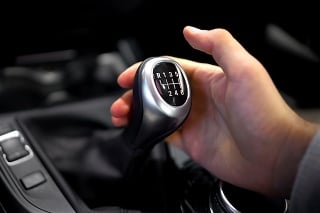 Male hand holding manual gearbox in car, test drive of new automobile, closeup