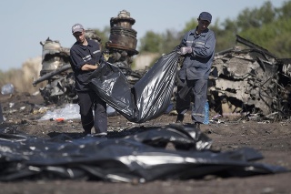 Záchranári nesú telo obete v plastovom vreci po páde letu MH17.