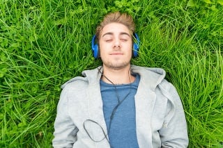 Young man with headphone listening to music in park