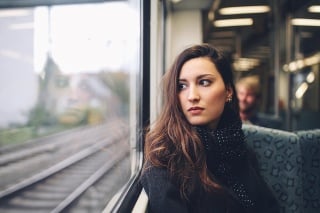 Vintage toned portrait of a young brunette woman riding in the Berlin S-bahn metro train. Only natural light used and some film emulation processing, taken on a late Autumn day in the afternoon.