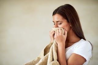 Shot of young woman enjoying the smell of freshly washed towels