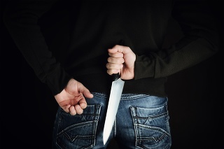 criminal with large sharp knife behind his back ready for robbery or to commit a homicide