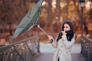 Autumn woman having problems in windy storm