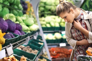 Closeup of early 30's attractive blond woman buying some vegetables at a local supermarket. She's standing in front of piles of vegetables and making choices.