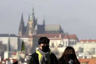 Turisti majú na tvári ochranné rúška počas návštevy Karlovho mosta v Prahe.