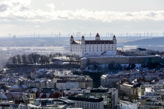 Bratislavský hrad a v pozadí veterná elektráreň v Rakúsku.