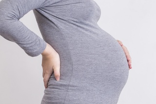 Pregnant woman has backache and touching her torso