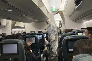 Pracovník v ochrannom oblečení meria teplotu cestujúcim z Hongkongu, ktorí pristáli v Ríme.