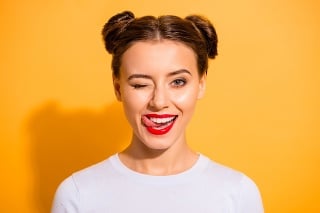 Close up photo of charming flirty adorable lady on holiday licking her lips pomade to attract boy men student have relationships isolated over vivid background dressed in white cotton jumper.