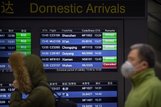Cestujúci kráčajú vedľa tabule s príchodmi, let z čínskeho mesta Wu-chan je zrušený.