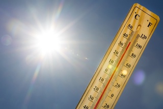 Mercury thermometer marking 39 degrees Celsius 100 Fahrenheit in a sunny day. Summer heat shown on mercury thermometer against the blue sky. Sunlight with sun flares.