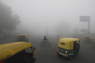 Muž jazdí na bicykli počas rannej hmly v indickom Naí Dillí 30. decembra 2019.