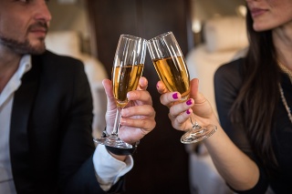Close up shot of champagne glasses that business couple is holding inside the private jet aeroplane.
