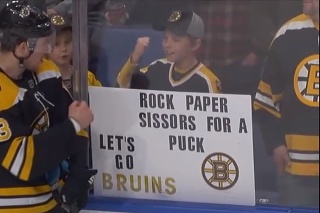 Malý fanúšik hrá počas prestávky s hráčom Bruins hru Kameň, papier nožnice