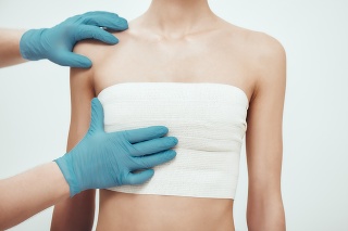 Increase your breast size. Cropped photo of woman waiting for plastic surgery while surgeons in blue medical gloves measuring her breast. Plastic surgery concept. Healthcare. Beauty concept.