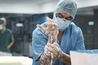 Veterinarian washing hands with soap. Male surgeon is preparing for surgery. He is in uniform at operating room.