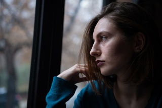 Young woman is sitting by the window and thinking.