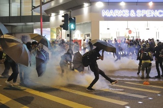 Demonštrant odkopáva slzotvorný granát počas potýčok s políciou v Hongkongu. 