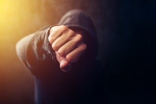 Crime, violence and bullying concept with hooded criminal person, selective focus on fist