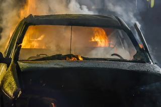Crashed car burning at night.