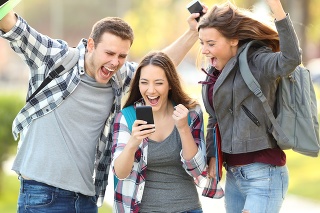 Three excited students checking exam grades online in a smart phone