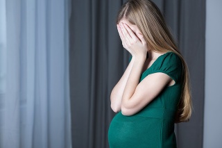 Image of a pregnant teenage girl hiding her face in her hands