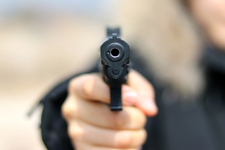 Woman pointing a gun at the target on soft background.