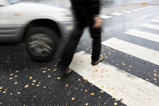 Man on pedestrian crossing in autumn, in danger of being hit by car