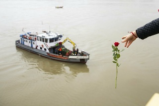 Žena hádže z Margitinho mosta červenú ružu do rieky Dunaj počas záchrannej operácie.