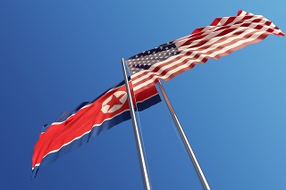 American and North Korean flags are waving with wind at opposite directions on a blue sky. Low angle view. Dispute and conflict concept. Horizontal composition with copy space. Great use for North Korea and United States of America related concepts.