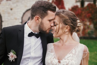 Gorgeous bride and stylish groom gently hugging and kissing outdoors. Sensual wedding couple embracing. Romantic moments of newlyweds. Wedding photo