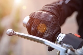 protective biker gloves on a motorcycle wheel with light effects. Driver accelerates, close-up