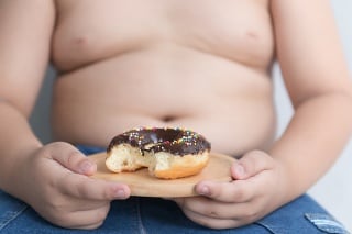 donut in hand obese fat boy on gray background, junk food can cause obesity.
