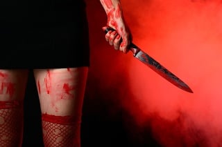 Mid section of woman wearing red stockings holding bloody knife in hand against smoky background