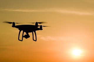 Quadrocopters silhouette against the background of the sunset. Flying drones in the evening sky.