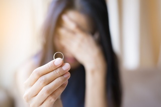 The woman holds the wedding ring and weeps.