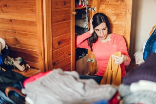 Young stressed woman is sorting out wardrobe
