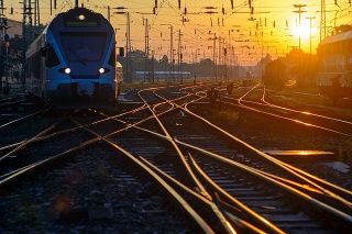 Sunrise, railroad junction, sunlit rails, frontal view of the train