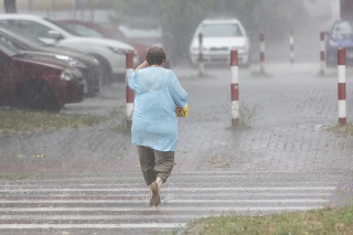 Žena prechádza cez ulicu počas búrky a silného dažďa v Podunajských Biskupiciach 