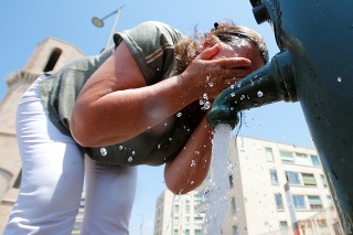 Žena v Marseille sa snaží osviežiť pri miestnej fontánke.