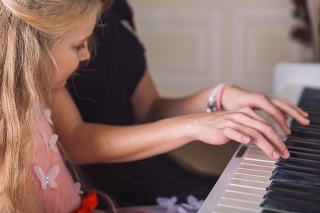 young woman teach little girl play piano