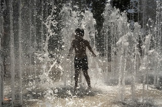 Dieťa sa ochladzuje vo fontáne počas horúčav 26. júna 2019 v Lyone.
